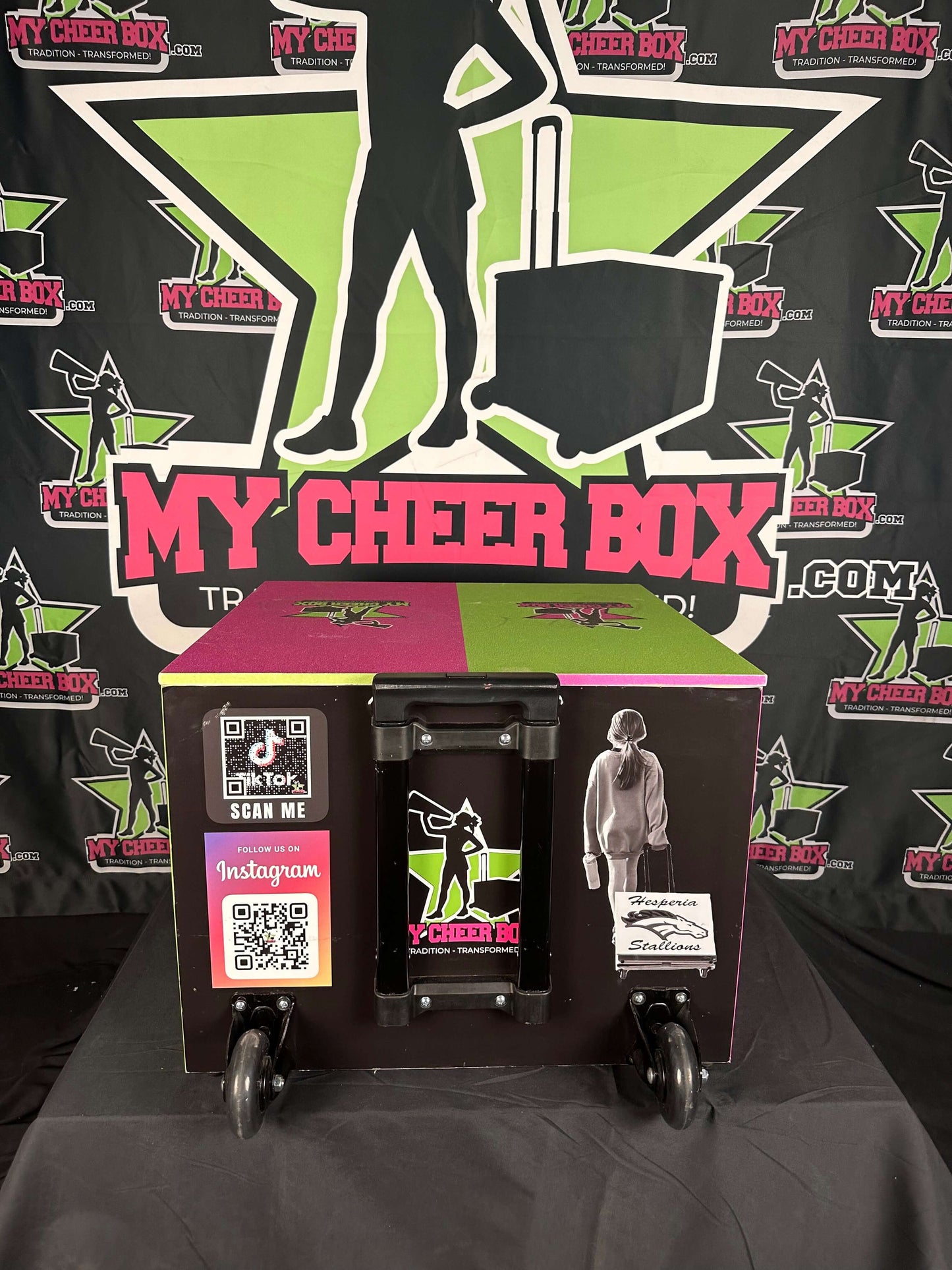 Fully customizable collapsible cheer box with QR codes and design elements on display against branded backdrop.